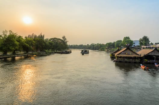 High angle view from bridge, beautiful landscape of Kwai Yai River at sunset and lifestyle of people on the waterfront in Kanchanaburi Province, Thailand