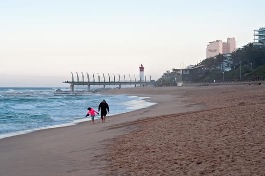 DURBAN, SOUTH AFRICA - JULY 11, 2016: People on the beach at Umhlanga Rocks, with the Millennium Pier and lighthouse in the background.