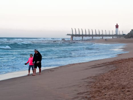 DURBAN, SOUTH AFRICA - JULY 11, 2016: People on the beach at Umhlanga Rocks, with the Millennium Pier and lighthouse in the background.