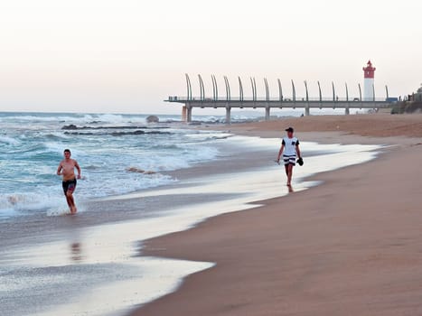 DURBAN, SOUTH AFRICA - JULY 11, 2016: People on the beach at Umhlanga Rocks, with the Millennium Pier and lighthouse in the background.