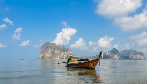 Seascape with limestone mountain and wooden long-tail boat at Pak Meng Beach in Trang province, Thailand