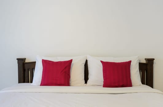 White bedroom with tidy King size bed and red pillows