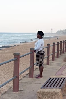 DURBAN, SOUTH AFRICA - JULY 13, 2016: Woman looks out to sea at the beach near the Millennium Pier and lighthouse in Umhlanga Rocks