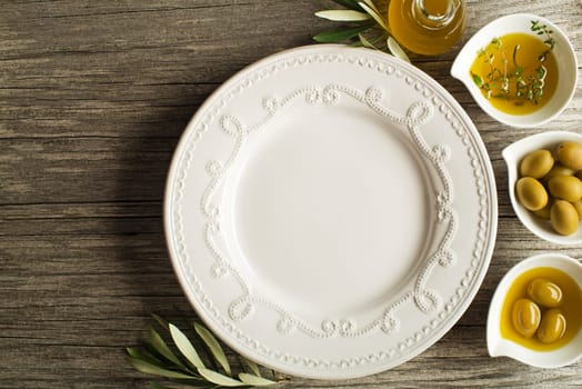 Olive oil with fresh herbs on wooden background