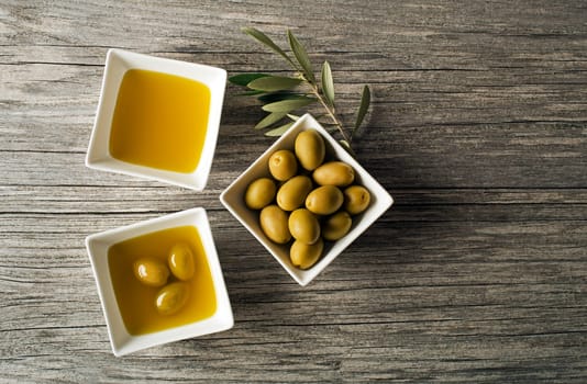 Olive oil with fresh olives on wooden background