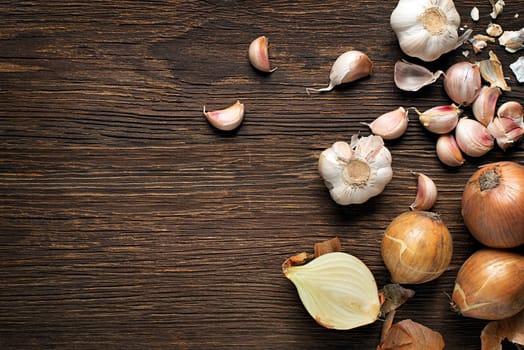 Garlic cloves and onions on wooden vintage background