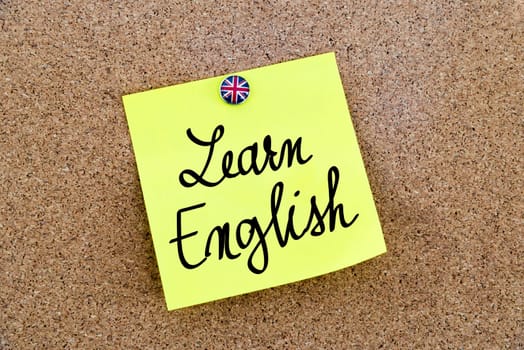 Yellow paper note pinned on cork board with Great Britain flag thumbtack, written text Learn English, British Business concept