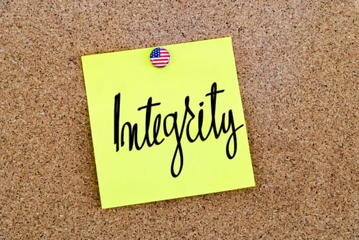 Written text Integrity over yellow paper note pinned on cork board
