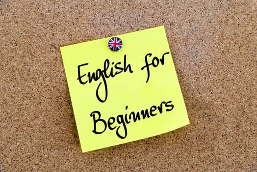 Yellow paper note pinned on cork board with Great Britain flag thumbtack, written text English For Beginners, British Business concept