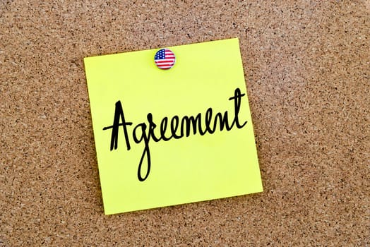Written text Agreement over yellow paper note pinned on cork board