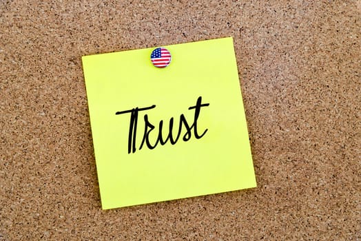 Written text Trust over yellow paper note pinned on cork board