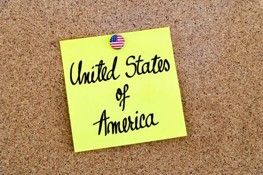 Written text United States Of America over yellow paper note pinned on cork board