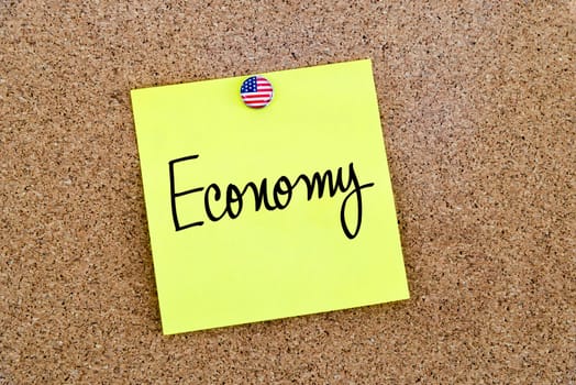 Written text Economy over yellow paper note pinned on cork board