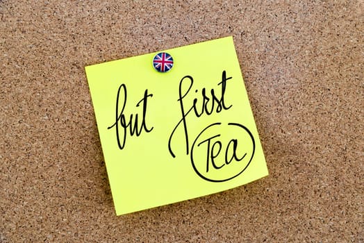 Yellow paper note pinned on cork board with Great Britain flag thumbtack, written text But First Tea, British Business concept