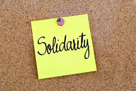 Written text Solidarity over yellow paper note pinned on cork board