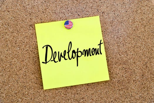 Written text Development over yellow paper note pinned on cork board