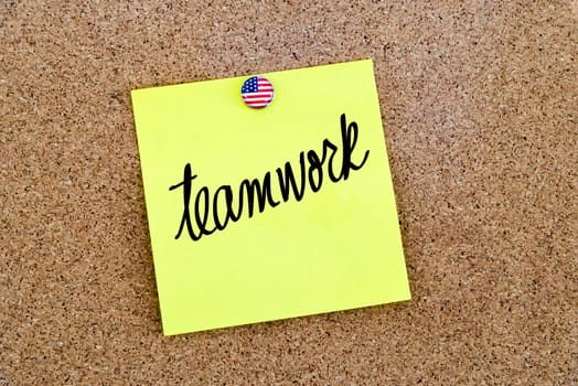 Written text Teamwork over yellow paper note pinned on cork board