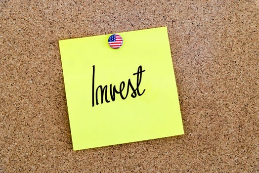 Written text Invest over yellow paper note pinned on cork board