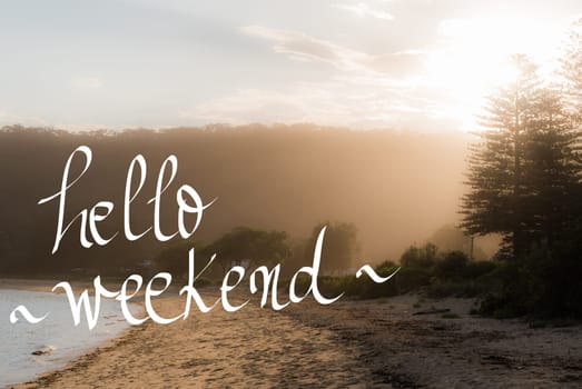 Hello Weekend Greeting. Handwritten motivational text over sunset calm sunny beach background with vintage filter applied