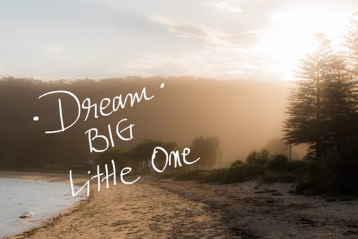 Dream Big Little One message. Handwritten motivational text over sunset calm sunny beach background with vintage filter applied