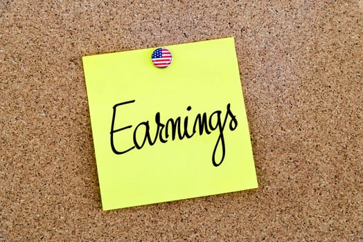 Written text Earnings over yellow paper note pinned on cork board