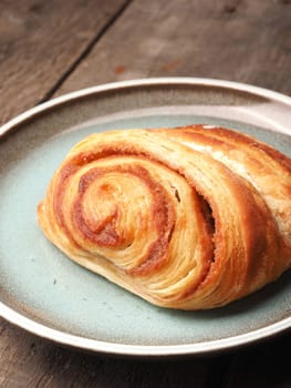 Sweet cinnamon pastry on a plate with a rustic wooden background
