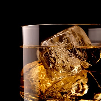 Close up shot of a glass of whiskey with ice cubes on a black background