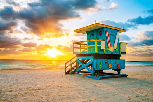 Miami South Beach sunrise with lifeguard tower and coastline with colorful cloud and blue sky.