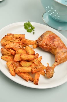 Roasted chicken with golden potato wedges on a white plate