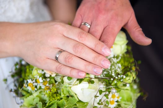 bride's and grooms hand with rings on flowers