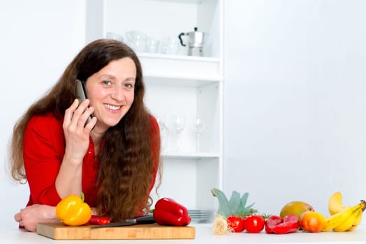 dark haired woman with red shirt in the kitchen is calling