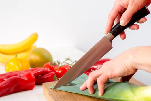 womans hand cutting vegetables with a big knife