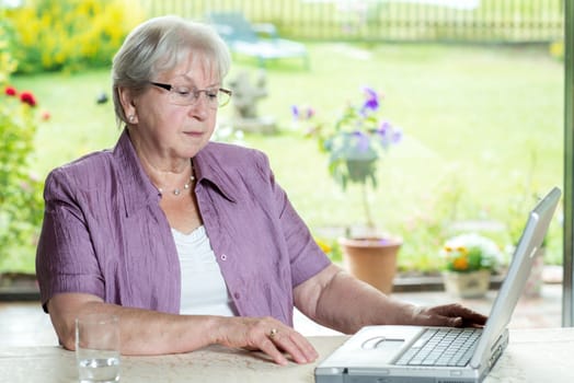 female senior is using computer at home