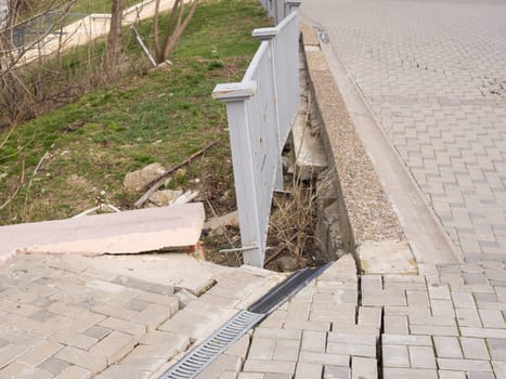 The destruction of the pedestrian walkway of stone tiles, and the brittle behavior of the fence