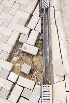 The destruction of the pedestrian walkway of stone tiles with drainage