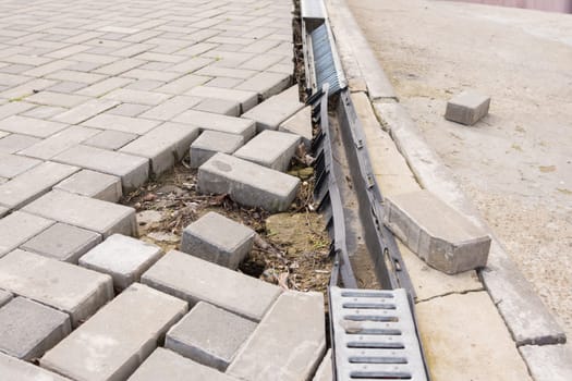 The destruction of the pedestrian walkway of paving with drainage and concrete road