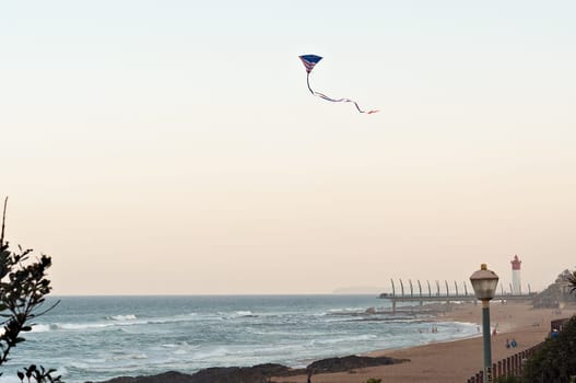 DURBAN, SOUTH AFRICA - JULY 13, 2016: An American Flag kite flies over the beach at Umhlanga Rocks, with the Millennium Pier and lighthouse in the background.