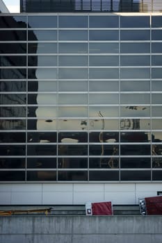 A baggage car with a trailer drives down a ramp on a modern exterior façade of a building at LAX Airport.