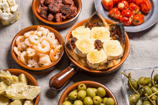 Tapas food, served in small bowls cold meat, goat cheese. A meal for sharing