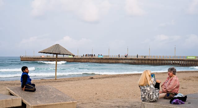 DURBAN, SOUTH AFRICA - AUGUST 17, 2015: People sitting near the pier at North Beach on the Golden Mile promenade.