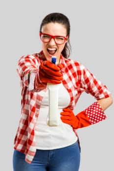 Pretty woman wearing gloves, using a cleaning spray and cleaning the house