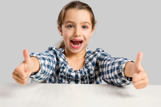 Little girl with thumbs up at school making drawings and painting