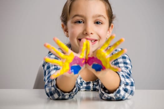 Cute smiling little girl with hands in paint