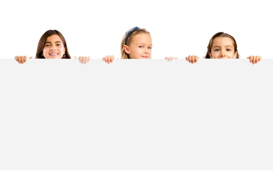 Cute litle girls holding a big white board with copyspace.
