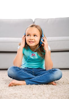 Little blonde girl at home listen music with headphones