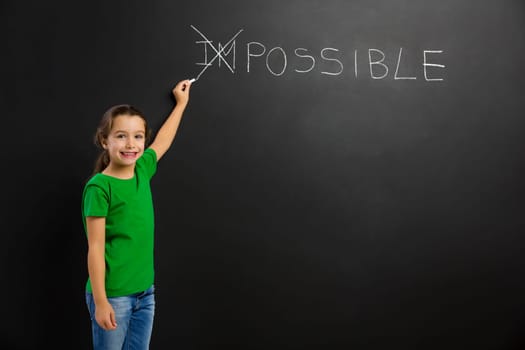 Smart little girl writing in a blackboard, with copy space