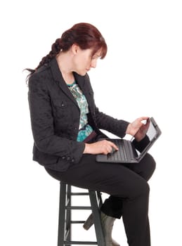 A middle age businesswoman sitting on a chair and working with .her laptop, isolated for white background..