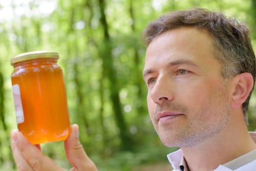 Man looking at jar of honey