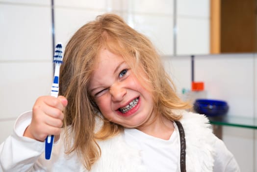little funny girl with retainer and toothbrush looking in to the camera