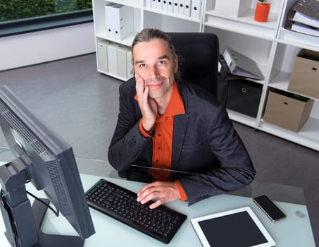 young business man at his desk looking friendly in to the camera